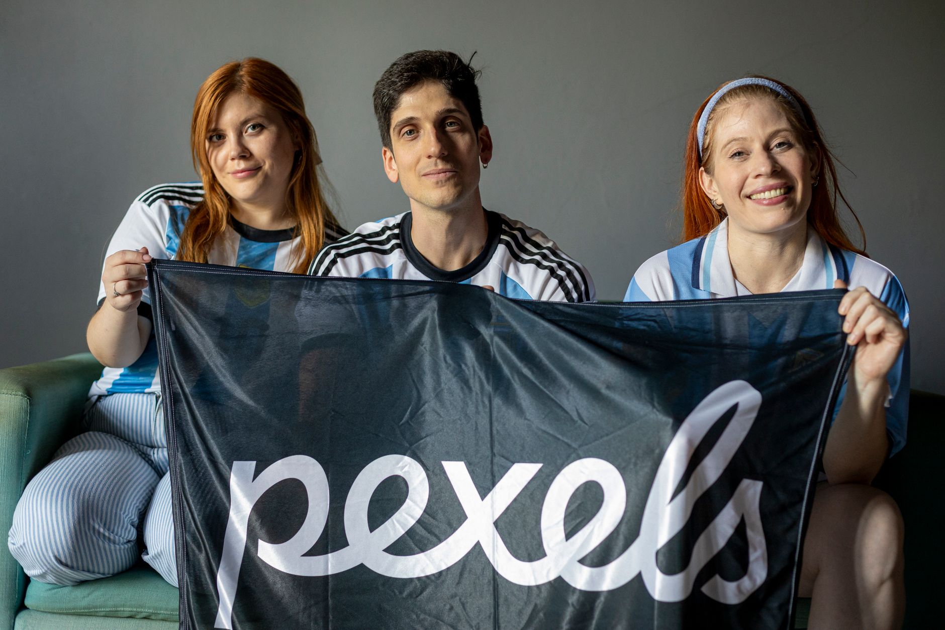 Tres adultos con una bandera con temática argentina, sonriendo en el interior.